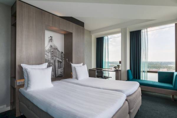 Doppelzimmer im Leonardo Hotel Amsterdam Rembrandtpark mit zwei Betten, Schreibtisch und Fenstern.