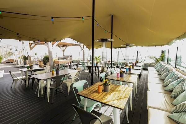 Terrasse des Leonardo Hotel Amsterdam Rembrandtpark mit Tischen und Stühlen unter einem Zeltdach.