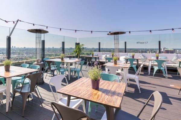 Dachterrasse des Leonardo Hotel Amsterdam Rembrandtpark mit Tischen und Stühlen.