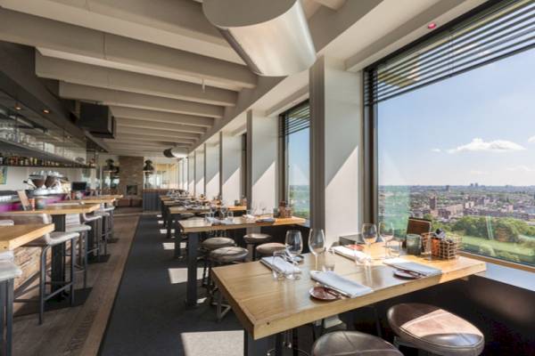 Innenansicht des Restaurants im Leonardo Hotel Amsterdam Rembrandtpark mit Blick auf die Stadt.