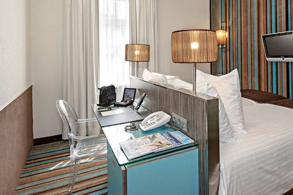 Hotelzimmer im WestCord City Centre Hotel mit Schreibtisch, Telefon und Fernseher.