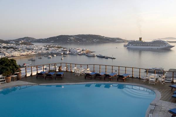Pool mit Liegen und Tischen auf der Dachterrasse des MykonosView Hotels mit einem Kreuzfahrtschiff im Hintergrund.