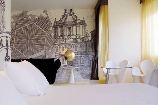 Schlafzimmer im Ripa Roma Hotel mit großem Bett, weißen Kissen und einer Wand mit architektonischem Wandbild.