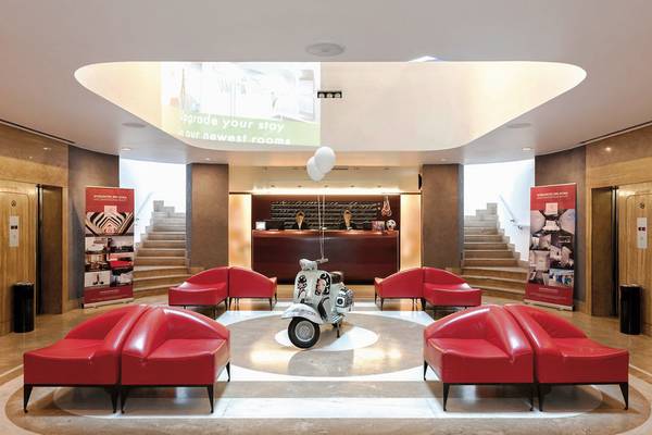 Hotellobby des Ripa Roma Hotels mit roten Ledersofas und einer Vespa in der Mitte.