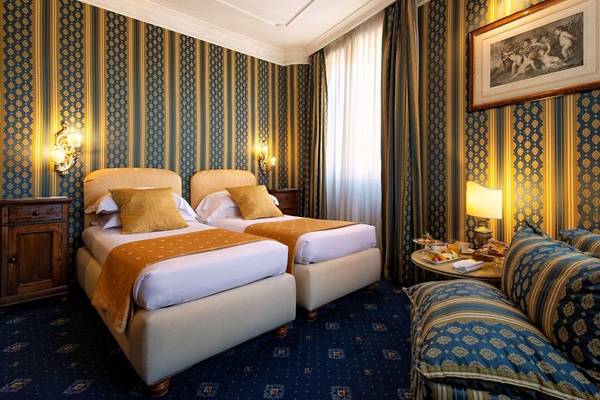 Doppelbettzimmer im Atlante Star Hotel mit blauen und gelben Wänden.