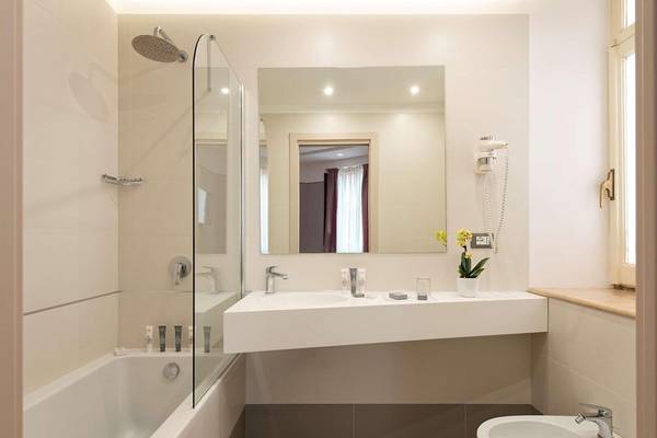 Badezimmer im Atlante Star Hotel mit Badewanne, Waschbecken und Spiegel.