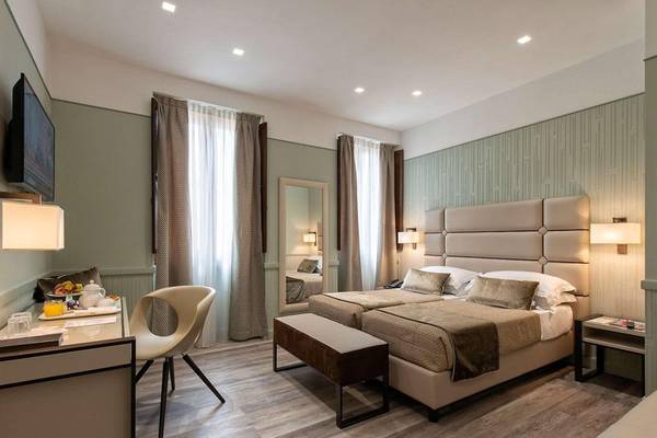 Innenansicht eines Doppelzimmers im Atlante Star Hotel mit zwei Betten, Schreibtisch, Stuhl und Fernseher.
