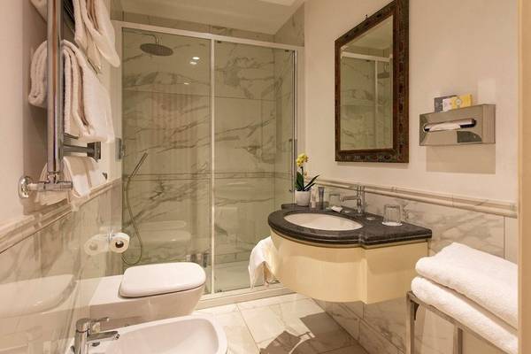 Badezimmer im Atlante Star Hotel mit Duschkabine, Waschbecken und Spiegel.