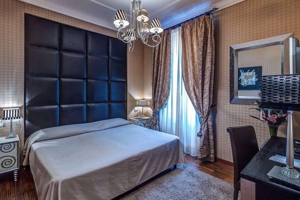 Schlafzimmer im Atlante Star Hotel mit Doppelbett, Nachttischen und Wandkunst.
