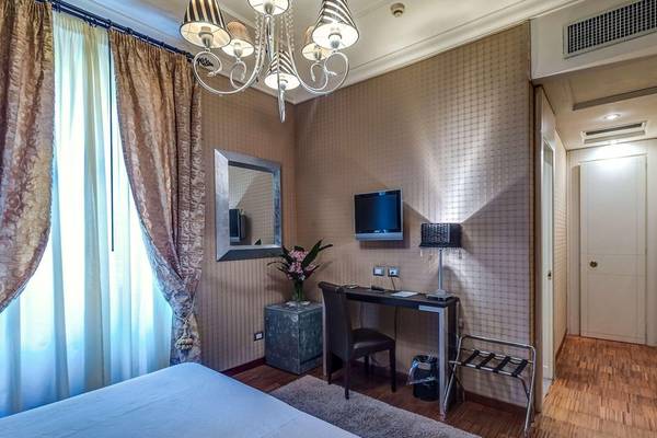 Schlafzimmer im Atlante Star Hotel mit Bett, Schreibtisch und Fernseher.
