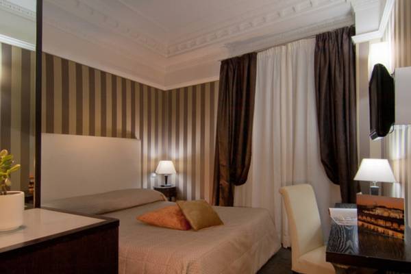 Ein elegantes Hotelzimmer im Atlante Star mit Bett, Nachttischen, Lampen und Schreibtisch.