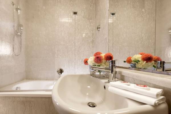 Badezimmer im Bettoja Hotel Massimo d'Azeglio mit Badewanne, Waschbecken und Blumenvase.