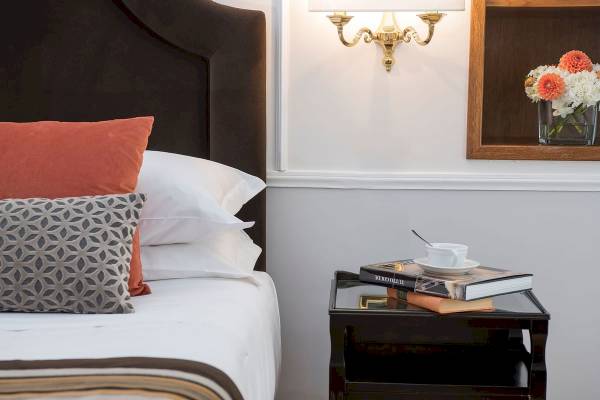 Hotelbett mit Kissen und Büchern auf dem Nachttisch im Bettoja Hotel Massimo d'Azeglio