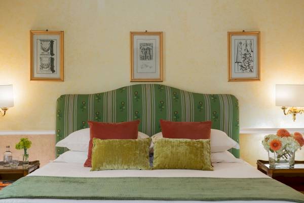 Schlafzimmer im Bettoja Hotel Massimo d'Azeglio mit grünem Kopfteil und drei kunstvollen Rahmen an der Wand.