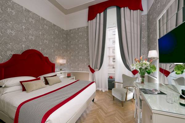 Hotelzimmer im Bettoja Hotel Massimo d'Azeglio mit rotem Kopfteil und weißen Wänden.