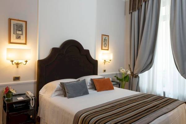 Schlafzimmer im Bettoja Hotel Massimo d'Azeglio mit Bett, Kissen und Nachttisch.