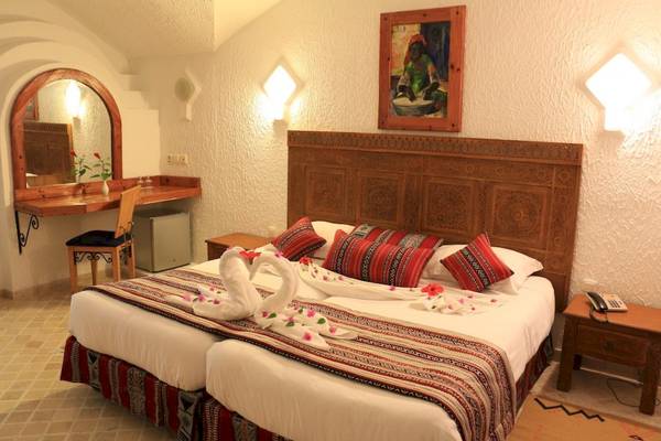 Doppelbett im Hotelzimmer des Lella Baya & Thalasso mit dekorativen Elementen und Wandmalerei.