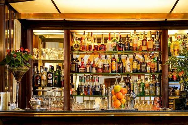 Die Bar im Bettoja Hotel Massimo d'Azeglio mit vollbestückten Regalen, Gläsern, Früchten und Pflanzen.