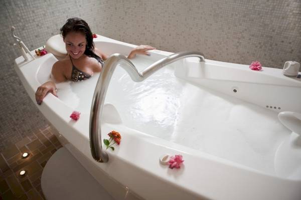 Frau in einer Badewanne im Lella Baya & Thalasso Hotel mit Blumen und Lächeln
