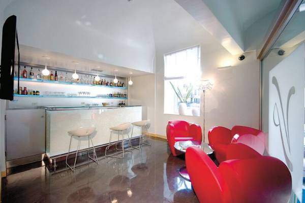 Hotellounge-Bereich mit Bar und roten Sesseln im Leonardo Boutique Hotel Rome Termini.