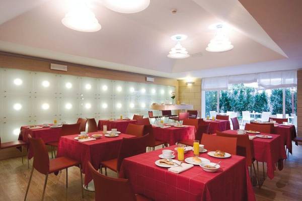Frühstücksraum im Leonardo Boutique Hotel Rome Termini mit roten Tischdecken und Frühstücksbuffets.