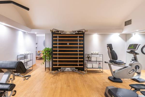 Fitnessraum im Leonardo Boutique Hotel Rome Termini mit verschiedenen Geräten und einer Pflanze.