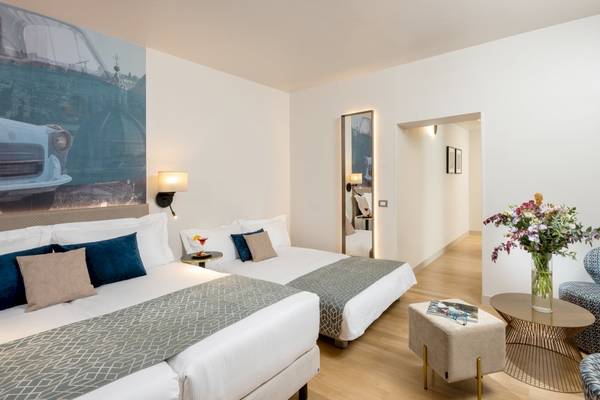 Doppelbettzimmer im Leonardo Boutique Hotel Rome Termini mit moderner Einrichtung und Kunstwerk an der Wand.