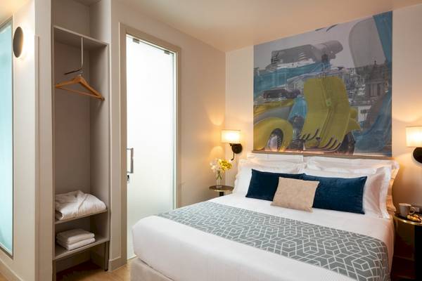 Schlafzimmer im Leonardo Boutique Hotel Rome Termini mit modernem Design und gelbem Motorradbild an der Wand.