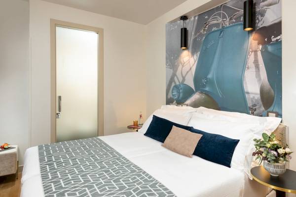 Doppelbett im Hotelzimmer des Leonardo Boutique Hotel Rome Termini mit Vespa Wandbild.