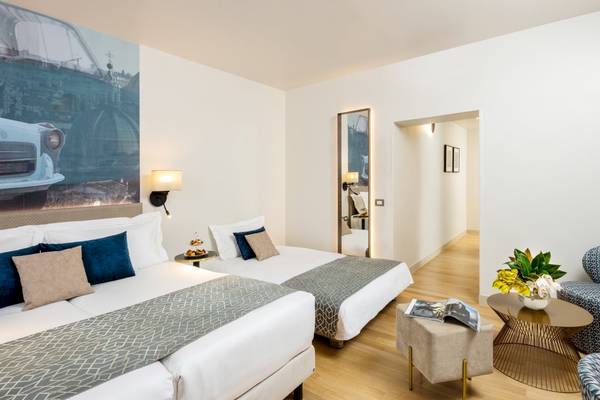 Doppelzimmer im Leonardo Boutique Hotel Rome Termini mit zwei Betten und einem Panoramabild eines Autos.