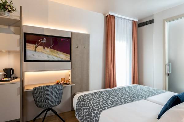 Zimmer im Leonardo Boutique Hotel Rome Termini mit Fernseher, Schreibtisch und Bett.