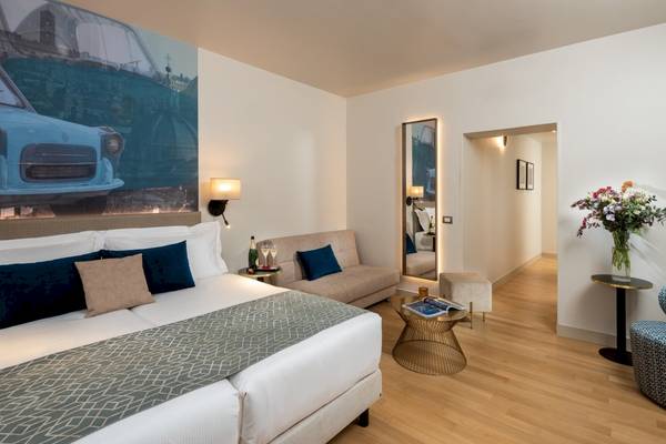 Leonardo Boutique Hotel Rome Termini Zimmer mit Doppelbett, Sofa, Tisch und Dekor