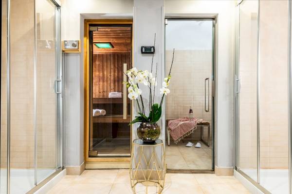 Saunabereich im Leonardo Boutique Hotel Rome Termini mit einer Glasvase voller Orchideen.