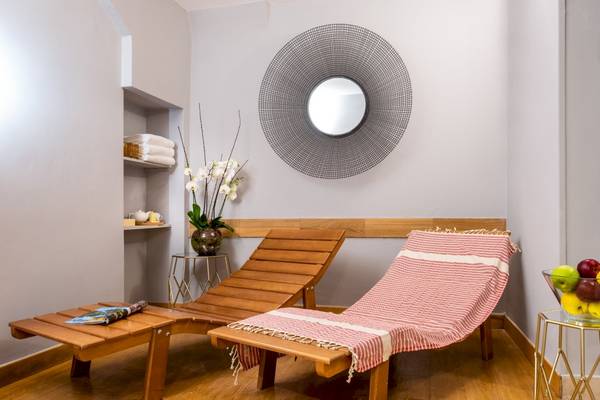 Loungebereich im Leonardo Boutique Hotel Rome Termini mit zwei Holzliegen, einer Tisch und Obstschale.