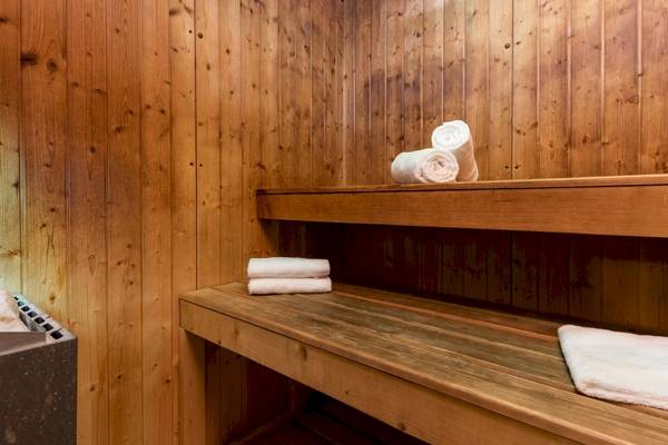 Sauna im Leonardo Boutique Hotel Rome Termini mit Holzwänden und Bänken, auf denen Handtücher bereitliegen.