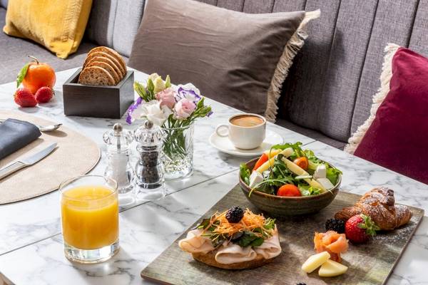 Frühstückstisch im Leonardo Boutique Hotel Rome Termini mit Früchten, Croissants, Salat und Kaffee.