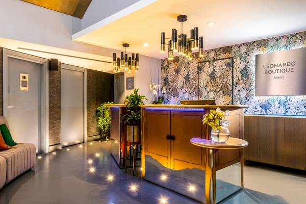 Empfangsbereich des Leonardo Boutique Hotel Rome Termini mit Rezeptionstresen, Sitzecke und dekorativen Elementen.