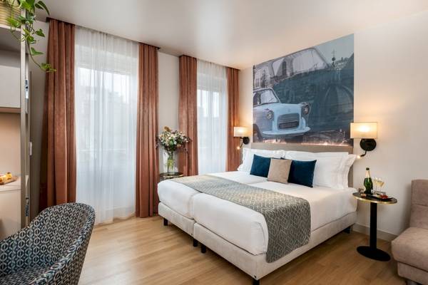 Doppelbett Zimmer im Leonardo Boutique Hotel Rome Termini mit Autotapete an der Wand.
