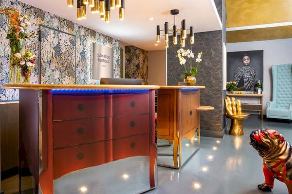 Empfangsbereich des Leonardo Boutique Hotel Rome Termini mit rotem Drawer und Blumenvase.