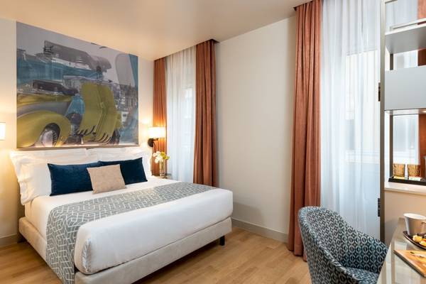 Schlafzimmer im Leonardo Boutique Hotel Rome Termini mit Doppelbett, Kunstwerk an der Wand und hellem Holzboden.
