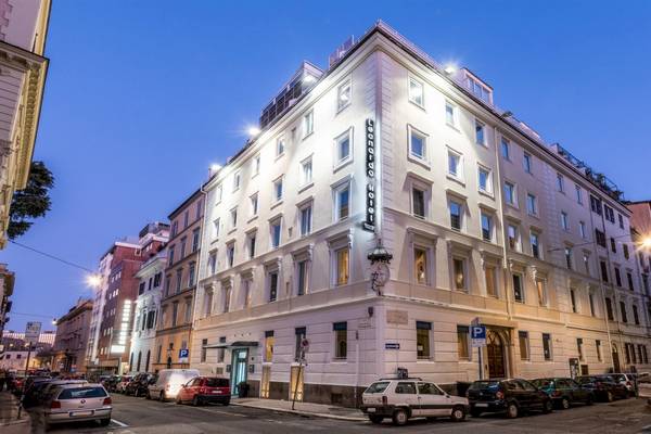 Außenansicht des Leonardo Boutique Hotel Rome Termini bei Nacht mit vielen Fenstern und leuchtenden Fassaden.