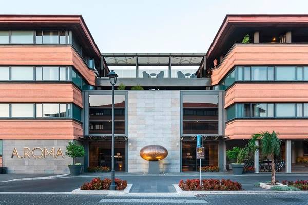 Außenansicht des A.Roma Lifestyle Hotels mit seinem markanten Eingang und bronzener Skulptur.