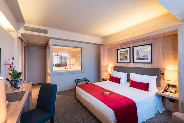 Innenansicht eines Zimmers im A.Roma Lifestyle Hotel mit einem großen Bett und Dekor.