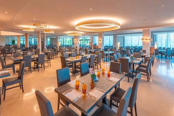 Innenansicht des Restaurants im A.Roma Lifestyle Hotel mit runden Deckenleuchten und blauen Stühlen.
