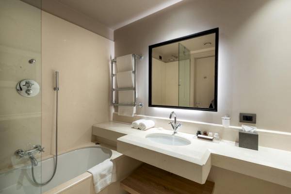 Badezimmer des A.Roma Lifestyle Hotel mit Badewanne, Waschbecken und Spiegel.