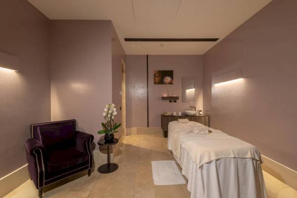 Behandlungsraum im A.Roma Lifestyle Hotel mit Massageliege, Sessel und Blumenvase