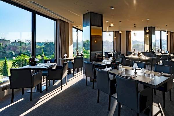 Innenansicht des Speisesaals des A.Roma Lifestyle Hotels mit großen Fenstern und modernen Möbeln.