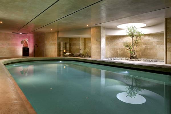 Innenpoolbereich des A.Roma Lifestyle Hotels mit Lounges und einem Baum.