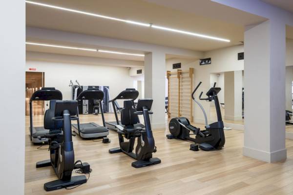 Fitnesscenter im A.Roma Lifestyle Hotel mit verschiedenen Trainingsgeräten auf Holzboden.