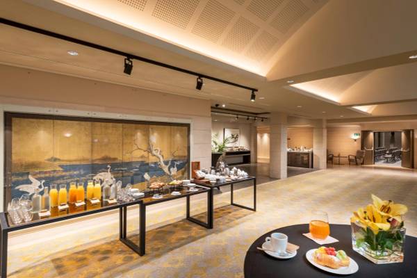 Frühstücksbereich im A.Roma Lifestyle Hotel mit langen Tischen, Getränken und Speisen.